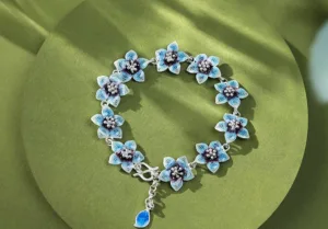 An exquisite silver bracelet featuring delicate light blue enamel flowers with intricate metalwork.