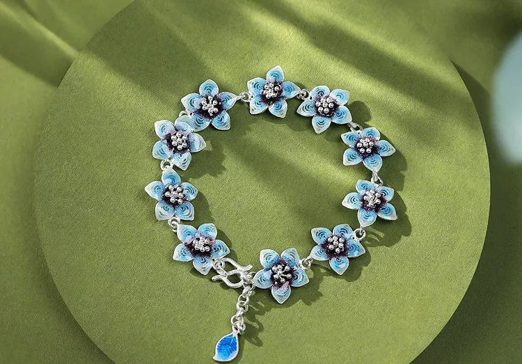An exquisite silver bracelet featuring delicate light blue enamel flowers with intricate metalwork.