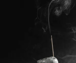Thin, delicate wisps of smoke rising from a natural incense stick, illustrating purity and calm.