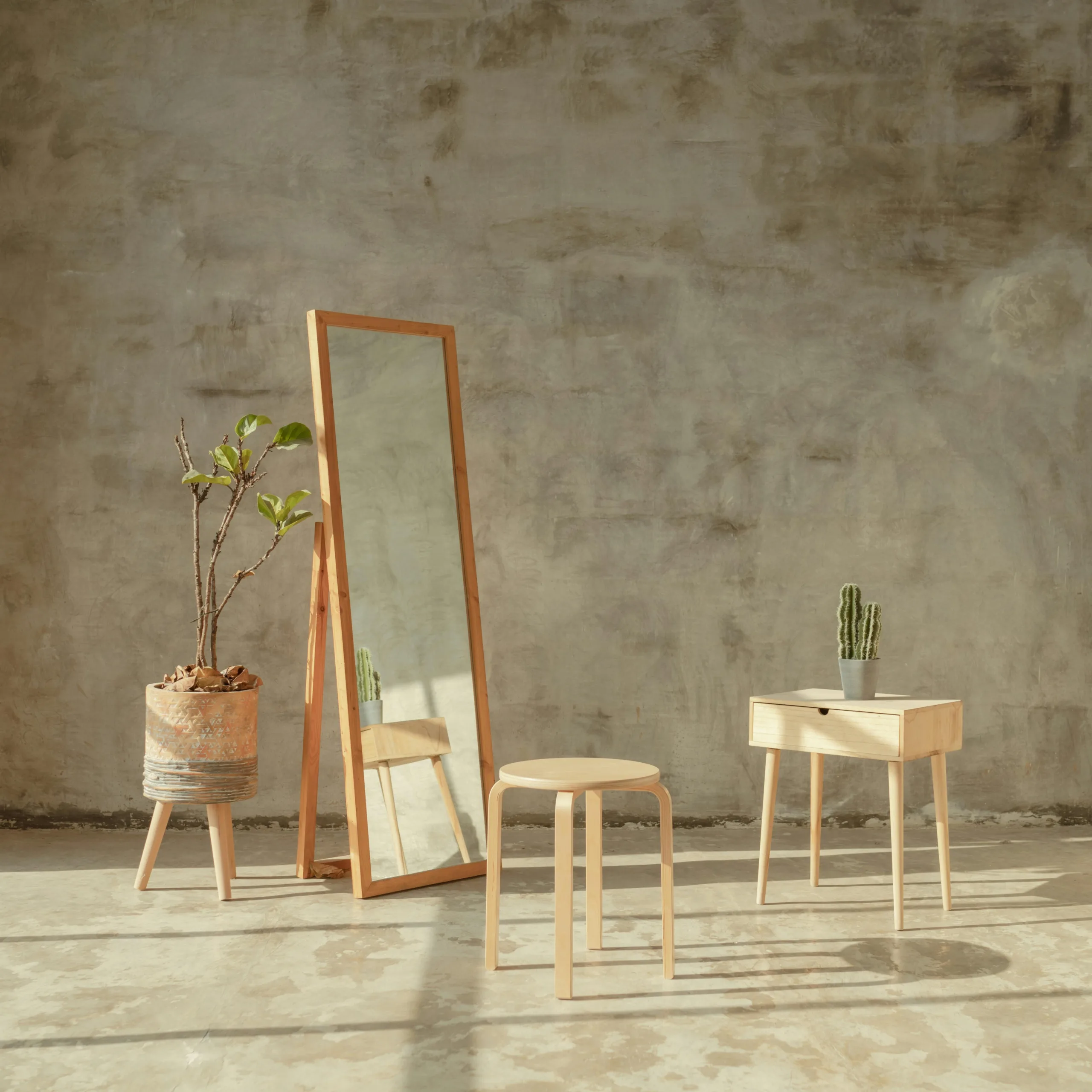A minimalist room with a wooden mirror, a stool, and potted plants against a concrete wall.